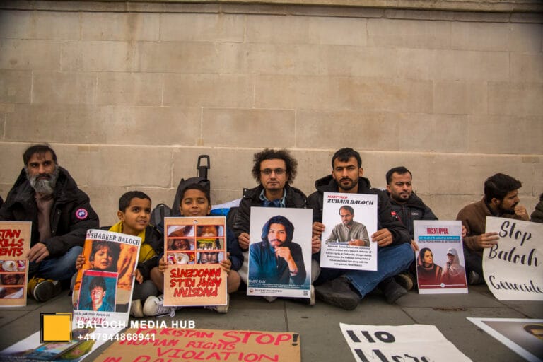 Aomar Karim holding a photo of a missing person during a Balochistan protest in London, alongside other demonstrators