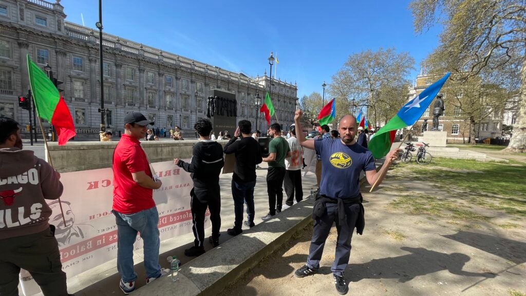 Sacha Ismail raises his fist while holding a Balochistan flag during the BNM UK Chapter protest outside 10 Downing Street, London, on 8 April 2026.