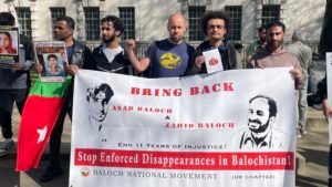 Baloch Activists Stage Protest Outside 10 Downing Street Demanding End to Human Rights Abuses in Balochistan Baloch political activist Aomar Karim (right) and trade union activist Sacha Ismail (centre, raised fist) stand with fellow Baloch activists outside 10 Downing Street, London, holding a banner demanding the return of enforced disappearance victims Asad Baloch and Zahid Baloch, during the Baloch National Movement UK Chapter protest on 8 April 2026.